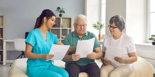 Nurse discussing documents with an elderly couple.